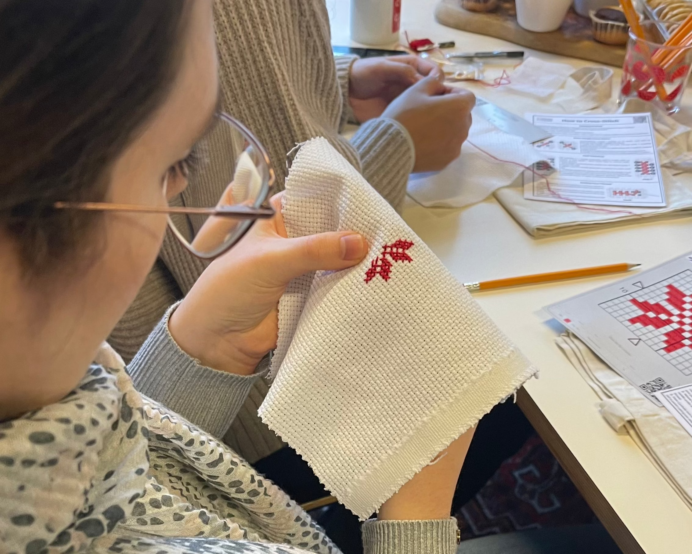 Close-up of a girl focused on stitching a detailed Tatreez pattern with needle and thread.