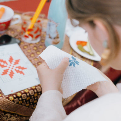 Close-up of a girl carefully stitching a Tatreez design with thread and needle.