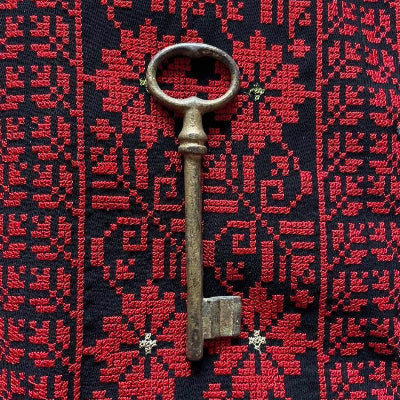 Traditional Palestinian Tatreez embroidery in red stitched on black fabric, featuring an old Palestinian door key symbolizing heritage and resilience.