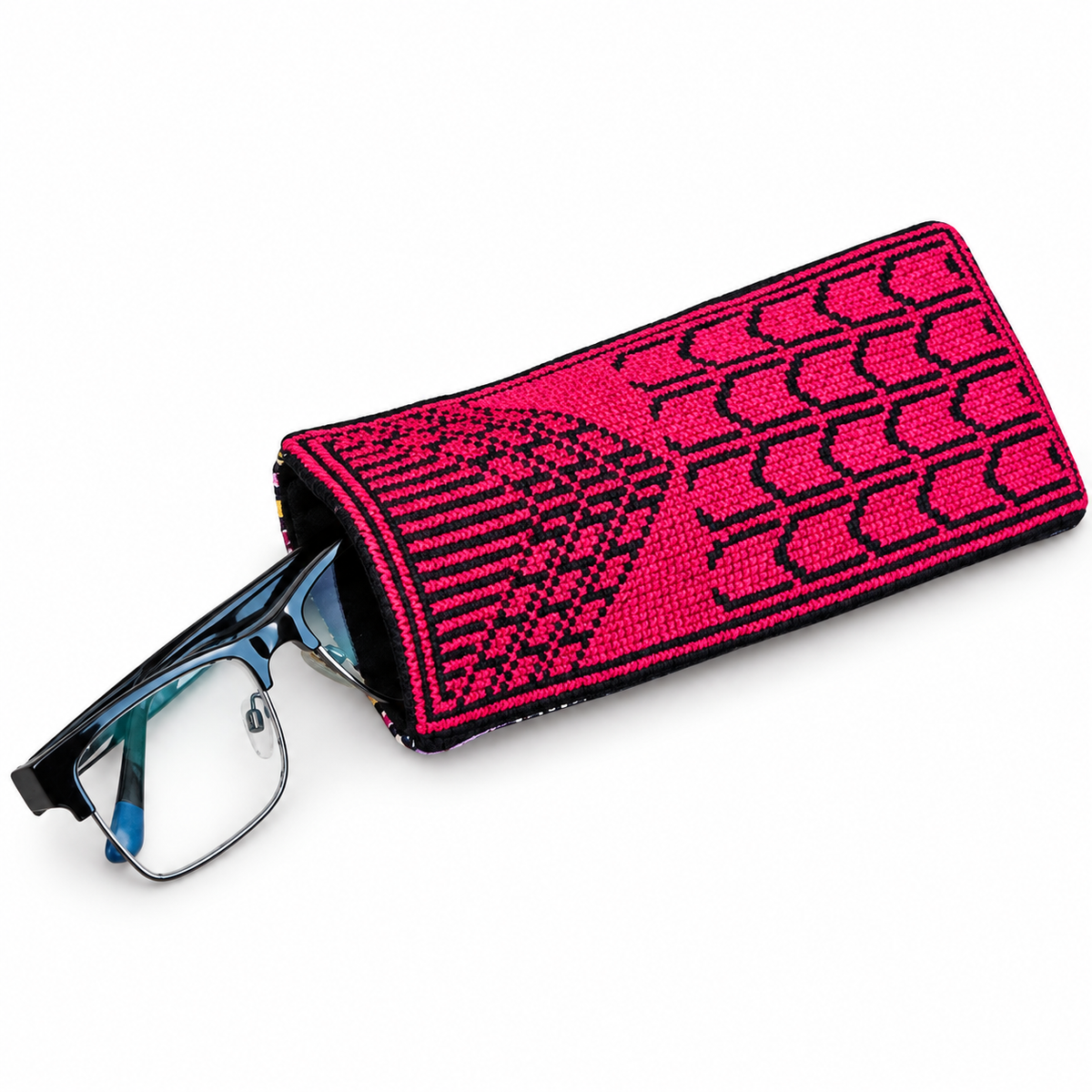 Perspective view of the handmade Sabla eyeglasses case, featuring a red Palestinian Tatreez pattern embroidered on black fabric with a pair of glasses partially inserted.
