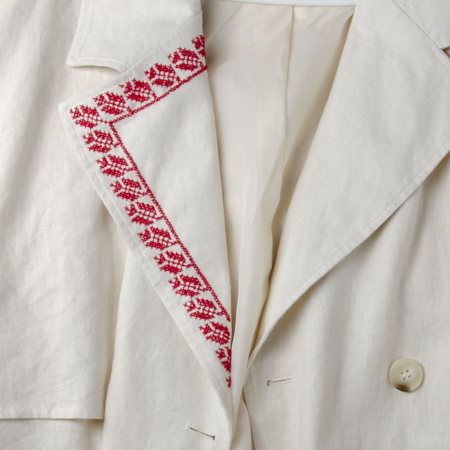 Traditional Palestinian tatreez embroidery stitched along the sleeve of a light-colored jacket using red cross-stitch patterns.