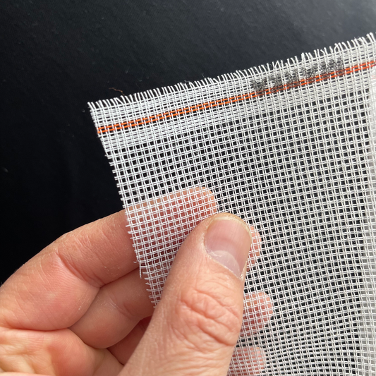 Hand holding white 11ct waste canvas showing texture and flexibility