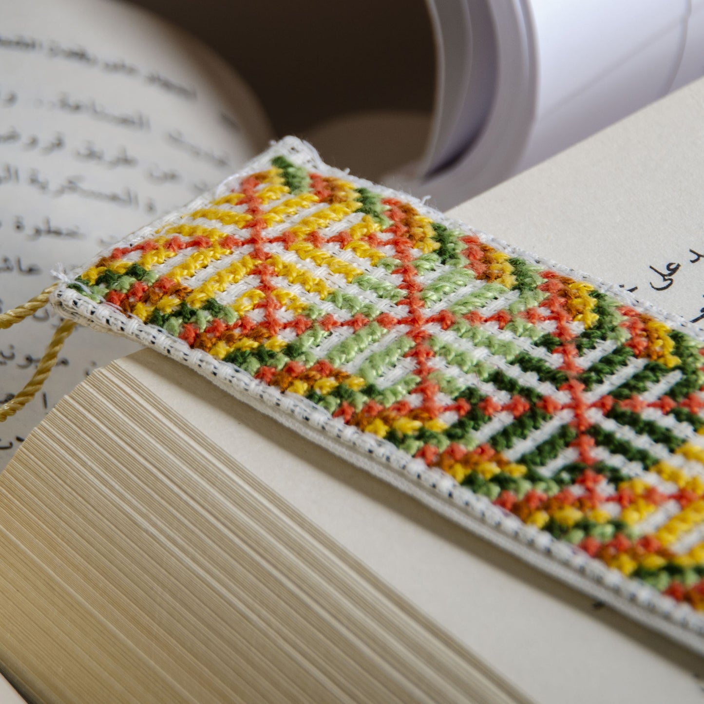 Handmade Palestinian bookmark with geometric tatreez embroidery in reading setting